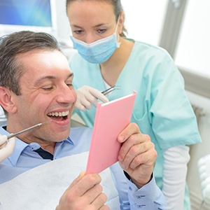 A man smiling in a mirror at his dental crown