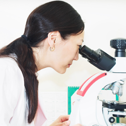 Female lab technician looking in microscope
