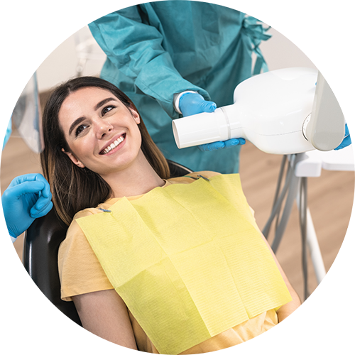 Woman in the dental chair grinning up at her dentist