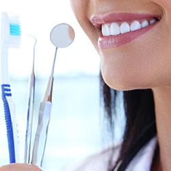 Smiling woman holding toothbrush and dental tools