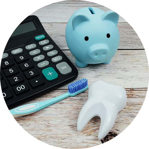 Blue piggy bank, calculator, model tooth, and toothbrush on wooden surface