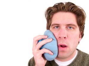 Man holding ice pack on cheek